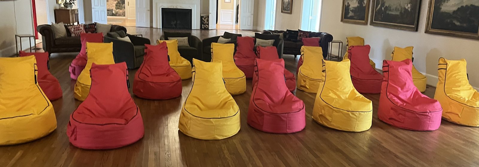 Red and yellow Bean Bag Rental Co high-back bean bag chairs arranged across a country club ballroom floor