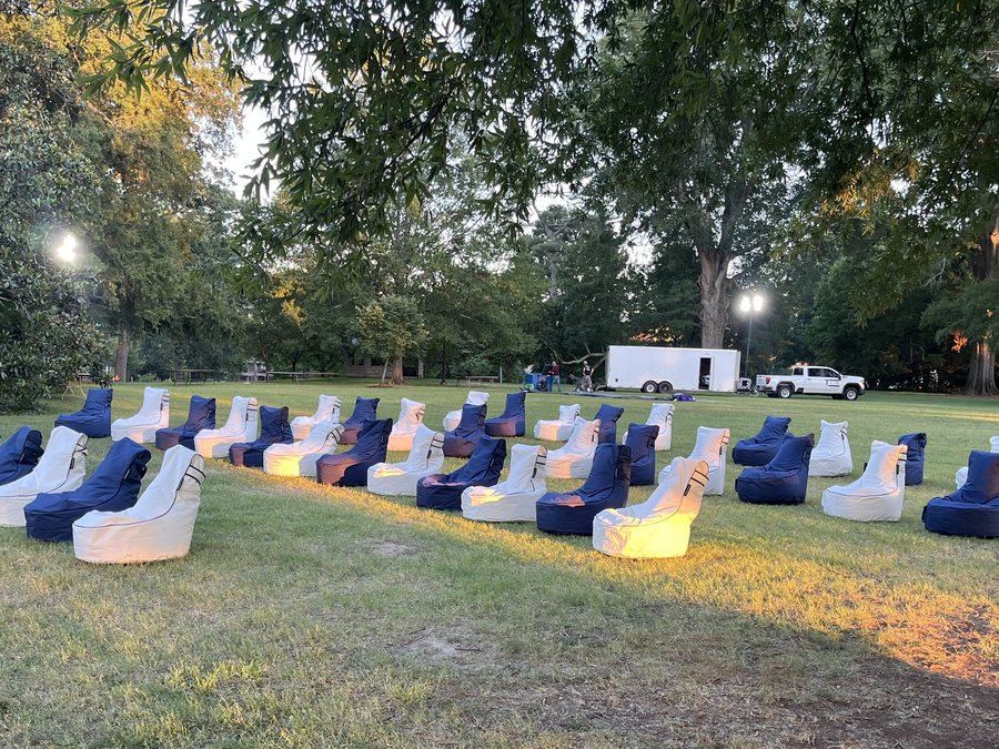 Curved rows of navy and white bean bag chairs arranged on a Duke University lawn at dusk, with the delivery trailer behind
