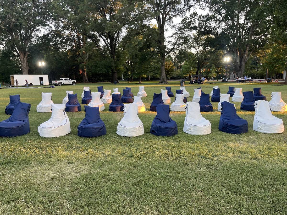 Forty bean bag chairs in curved rows on a campus lawn at golden hour