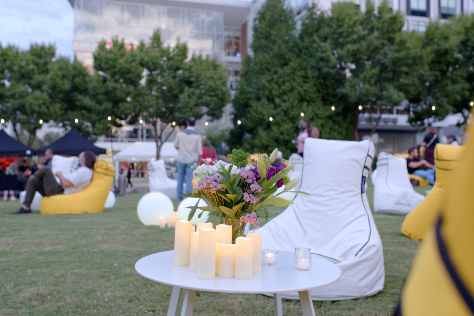 Flameless candles and fresh florals on a white lounge table beside a white bean bag chair